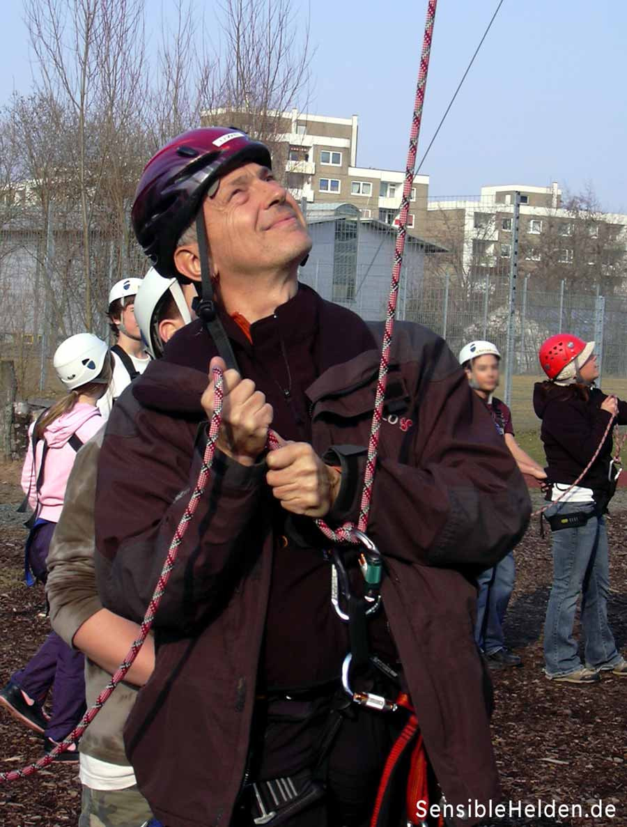 Sicherheitsausrüstung im Hochseilgarten Worms – hier Götz Uwe Kreß mit Helm, Gurt beim professionellen Sichern eines Teilnehmers