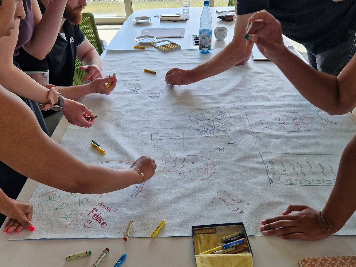 Kreative Zusammenarbeit im Workshop Workshop-Teilnehmende entwickeln kreative Ideen am Tisch