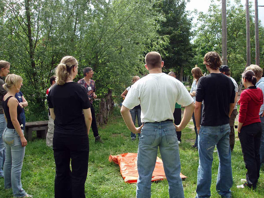 Gruppenleitung mit Klarheit und Sicherheit Trainer Götz Uwe Kreß steht vor einer Gruppe im Freien und leitet eine Übung an – Gruppenleitung Fortbildung mit Sicherheit und Empathie.