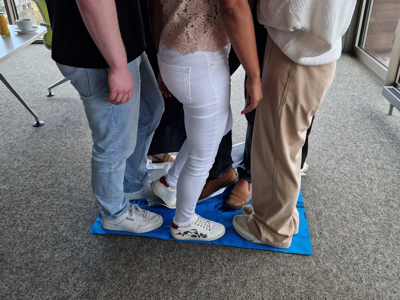 Zusammenhalt und Nähe im Team stärken Teamentwicklungs-Übung, Gruppe steht dicht zusammen auf Matte