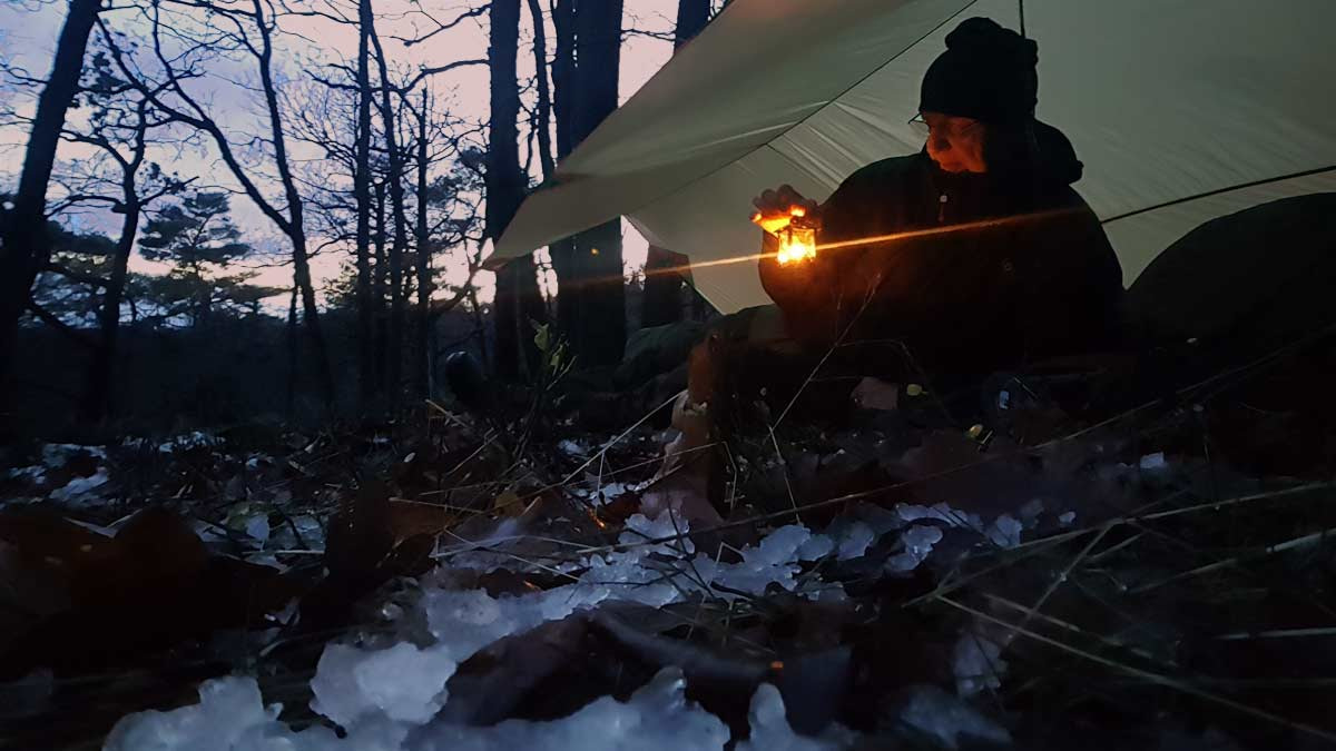 Licht und Schatten in den Raunächten: Mein Ritual im Wald Mentor Götz Uwe Kreß nachts im verschneiten Winterwald mit kleiner Laterne. Übergang vom Licht in die heilsame Dunkelheit der Raunächte für Hochsensible.