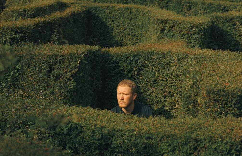 Symbolische Darstellung hochsensibler Charaktereigenschaften: Ein Mann sucht den Weg aus einem Irrgarten, Gedankenkarussell, Grübeln, kopflastig, zu viel denken.