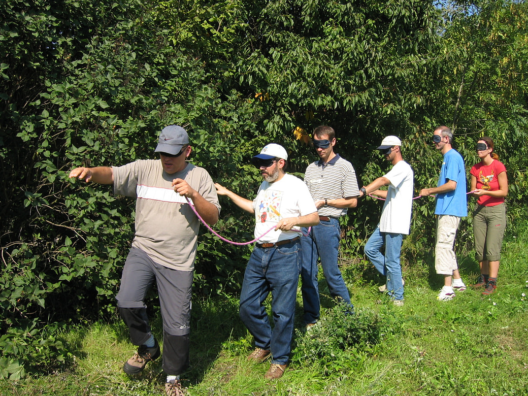 Team-ohne-Leitung-strukturieren-Uebung-outdoor Teammitglieder mit Augenbinden bei einer outdoor-Übung mit einem Seil erproben eine Teamstruktur ohne Leitung.