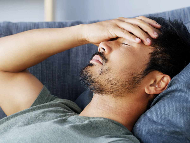 Chronische Überreizung: Auch Männer sind betroffen Chronische Überreizung bei hochsensiblen Männern: Mann liegt erschöpft auf Sofa mit Hand vor Gesicht. Zeigt Symptome langfristiger Überstimulation wie Kopfschmerzen, Erschöpfung und Überforderung bei hochsensiblen Menschen.